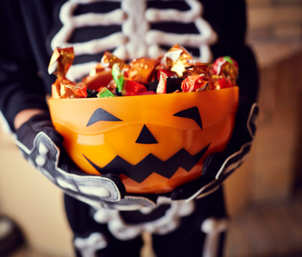 Boy in skeleton costume holding bowl full of candies